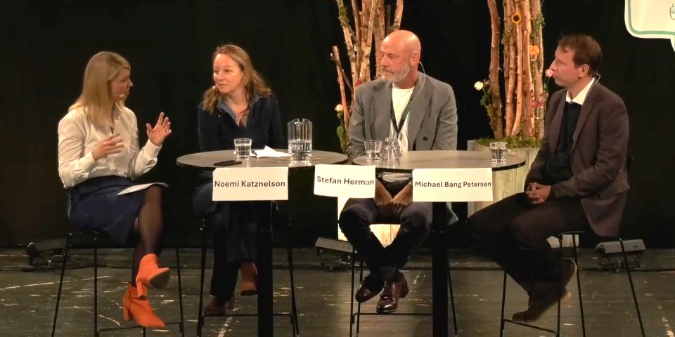 Fire mennesker sidder på stole på scene