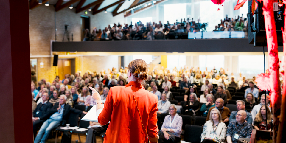 Person holder tale på scenen til Uddannelsesdebatten