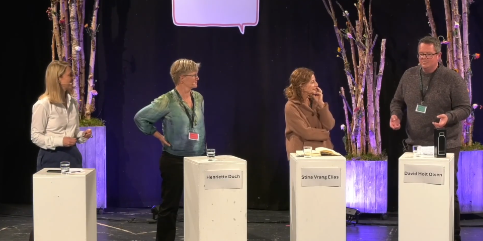 Fire mennesker står ved panelborde på scene