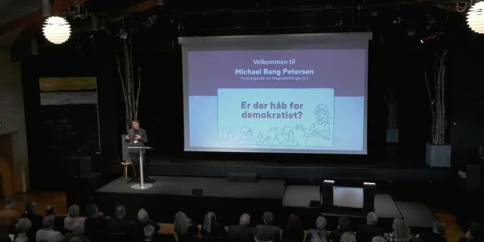 Mand står på scene og snakker