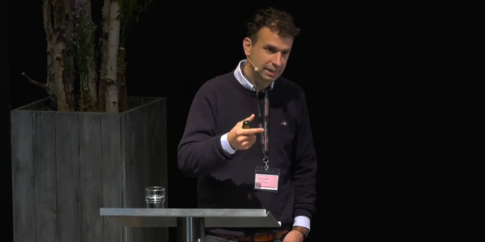 Mand står på scene og snakker